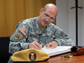 El jefe del séptimo Mando de Apoyo Civil, general Paul M. Benanati, firma en el libro de honor del tercer Batallón.